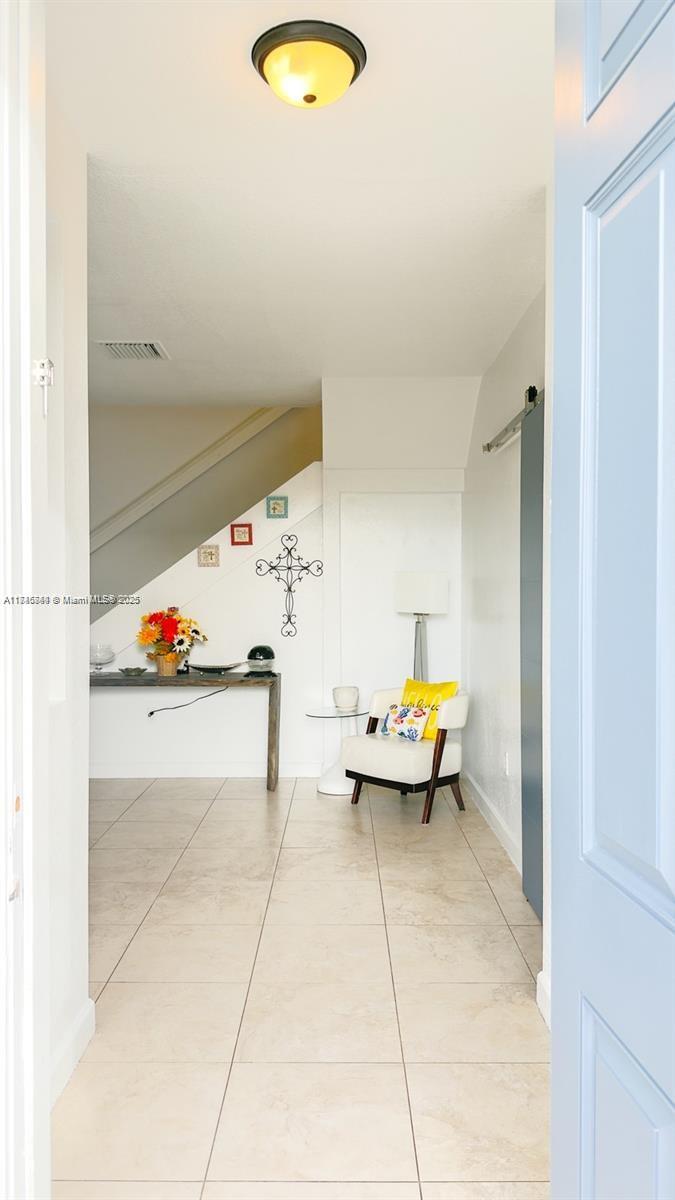 A tiled entryway features a staircase, a console table with flowers, and a white chair — 1001 NE 208th St, Miami FL 33179, MIAMI, FL