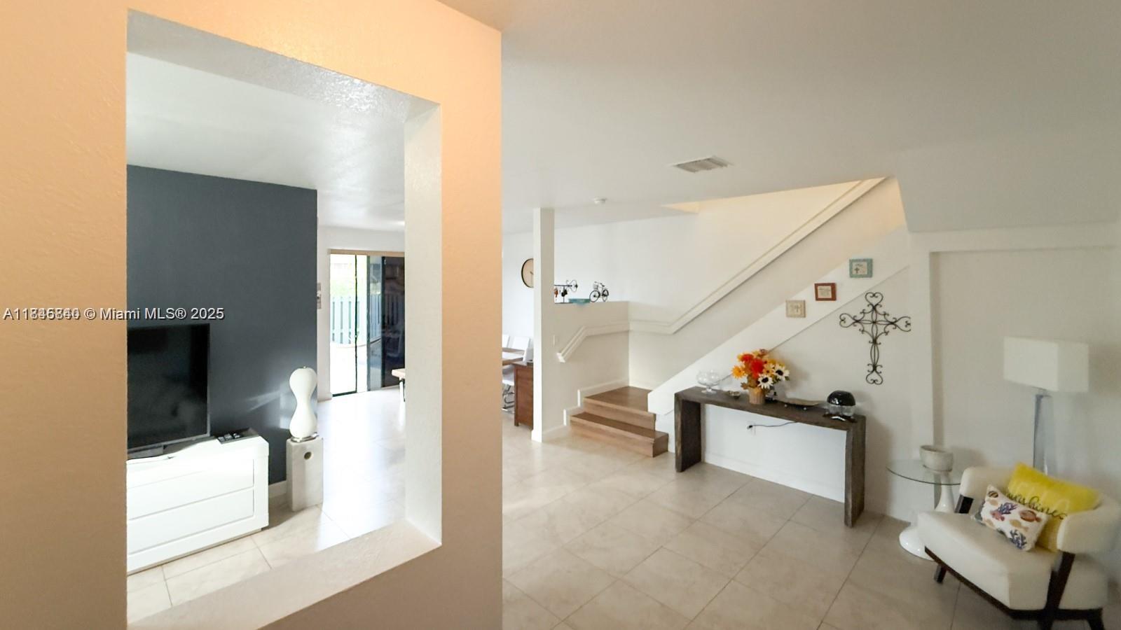A living area features a staircase, a console table, and a view into another room — 1001 NE 208th St, Miami FL 33179, MIAMI, FL