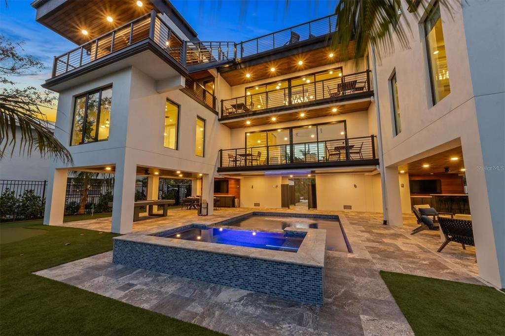 A modern multi-story house features a swimming pool, spa, and multiple balconies at dusk — 540 S POLK DRIVE, SARASOTA, FL