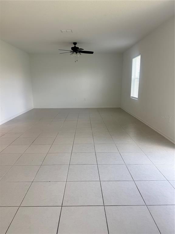 An empty room features light-colored tile flooring, white walls, and a ceiling fan — 2434 MCKINLEY DRIVE, LAKE WALES, FL