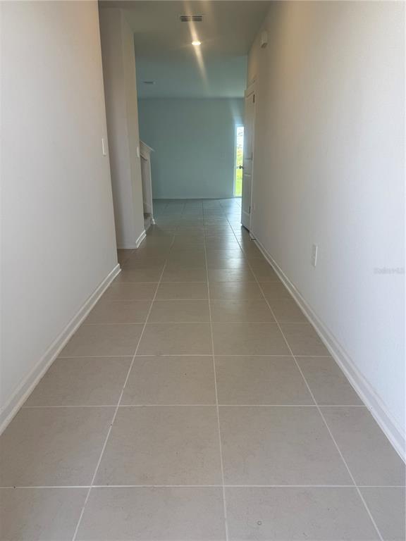 A long hallway with light-colored tile flooring leads toward an open living area — 2434 MCKINLEY DRIVE, LAKE WALES, FL