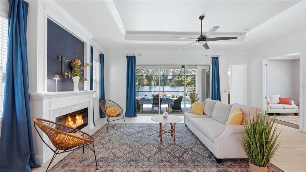 A living room with a fireplace, blue curtains, and a view of a backyard pool — 1850 MAGNOLIA STREET, SARASOTA, FL