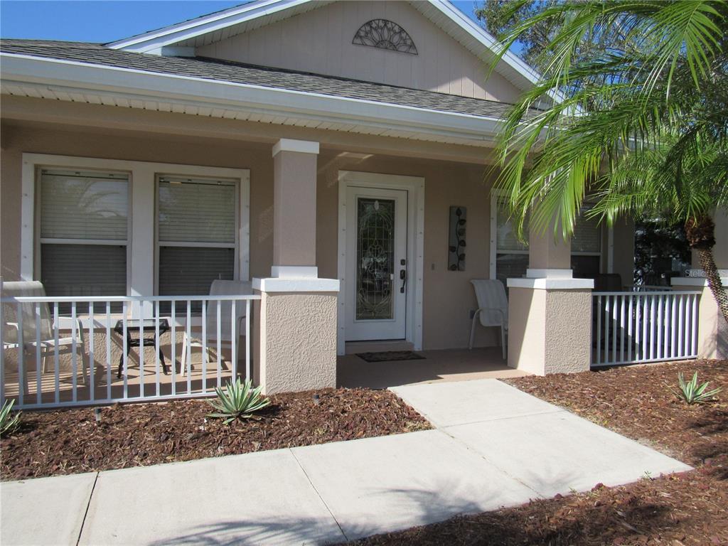 A front view of a house with a covered porch, white railings, and a glass-paneled door — 191 ALLWORTHY STREET, PORT CHARLOTTE, FL