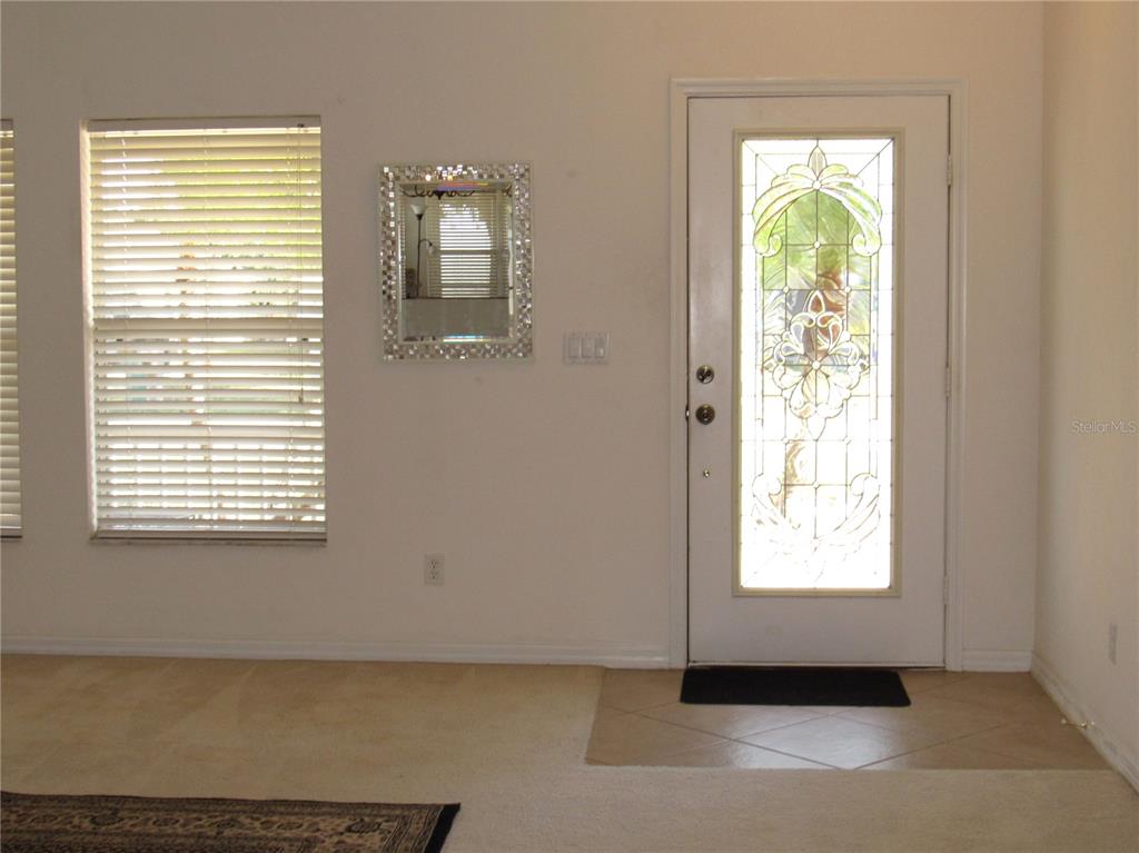 An entryway features a white front door with a decorative glass insert and a mirror — 191 ALLWORTHY STREET, PORT CHARLOTTE, FL
