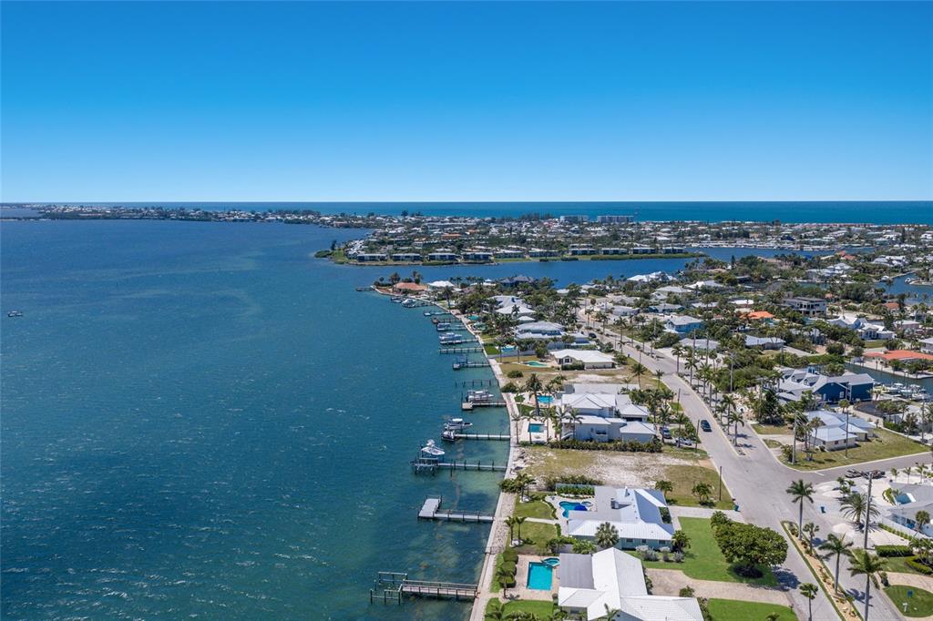 An aerial view shows waterfront homes with private docks along a bay under clear skies — 633 KEY ROYALE DRIVE, HOLMES BEACH, FL