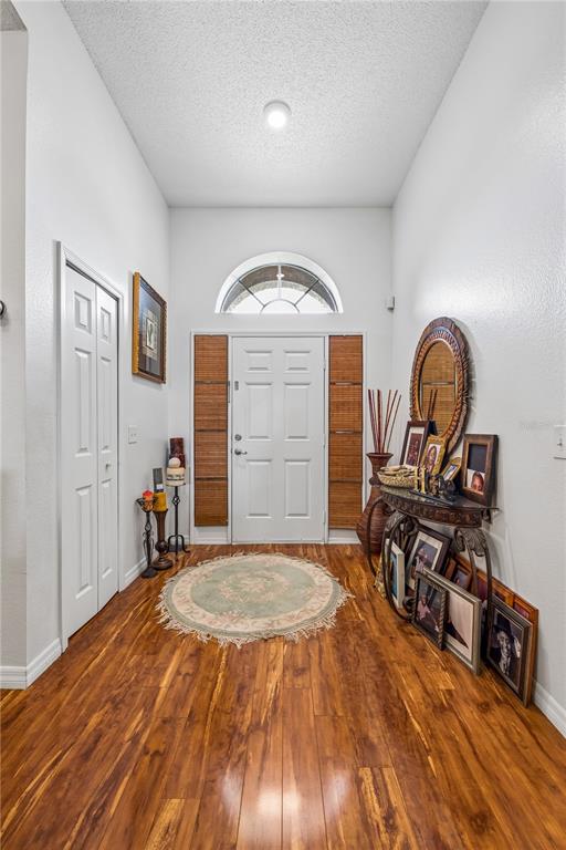 An entryway features wood flooring, a white front door with a transom window, and decor — 10337 LAXTON STREET, ORLANDO, FL