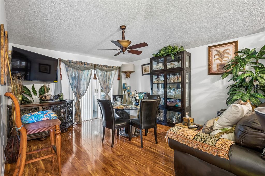 A dining area with a glass table, dark chairs, a china cabinet, and hardwood floors — 10337 LAXTON STREET, ORLANDO, FL