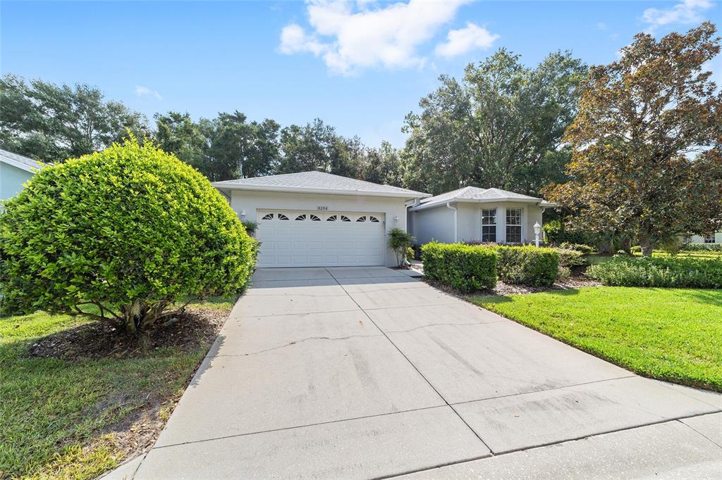 A single-story house with a white garage door, concrete driveway, and manicured landscaping — 8298 SW 79TH CIRCLE, OCALA, FL