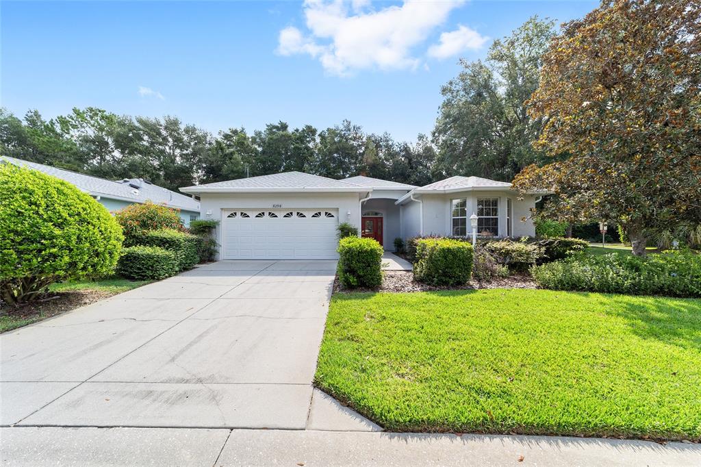 A single-story house with a white garage, red front door, and a green lawn — 8298 SW 79TH CIRCLE, OCALA, FL