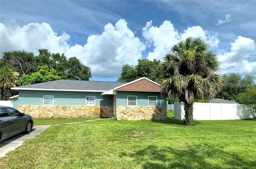 A single-story house with a stone facade, teal siding, and a palm tree in front — 709 E 119TH AVENUE, TAMPA, FL