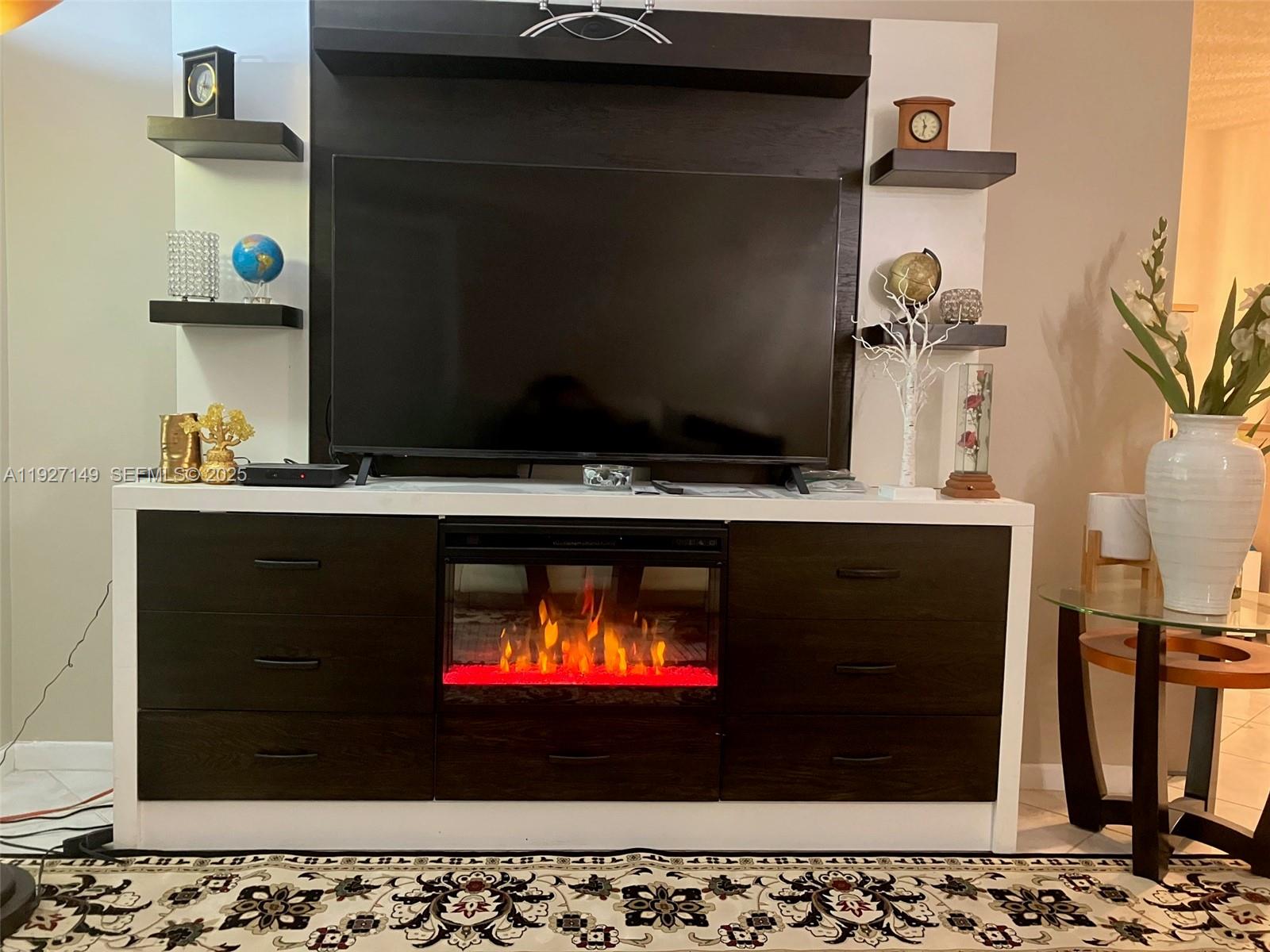 A living room features a large television mounted above an electric fireplace media console — 5174 Lakefront Blvd # C, Delray Beach FL 33484, DELRAY BEACH, FL