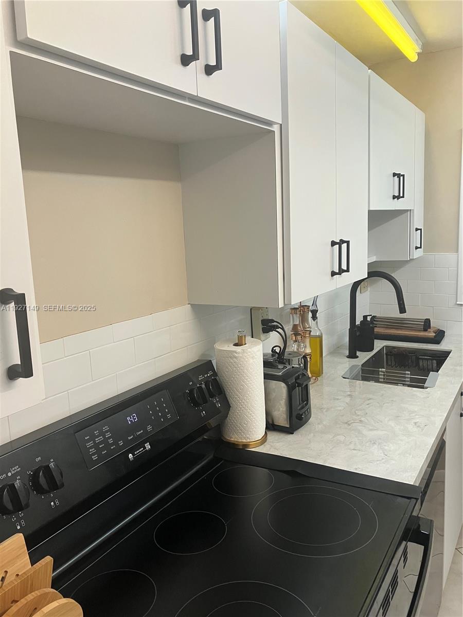 A kitchen features white cabinets, black hardware, a black electric stove, and a light countertop — 5174 Lakefront Blvd # C, Delray Beach FL 33484, DELRAY BEACH, FL