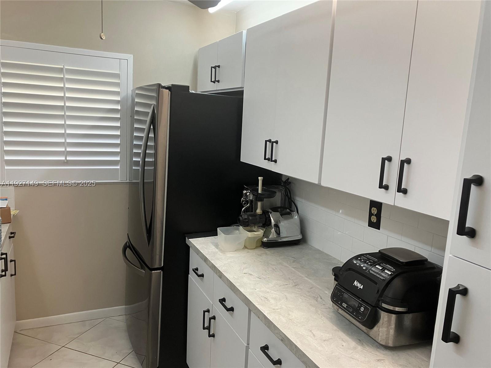 A kitchen features white cabinets, a black refrigerator, a Ninja appliance, and stone-look countertops — 5174 Lakefront Blvd # C, Delray Beach FL 33484, DELRAY BEACH, FL