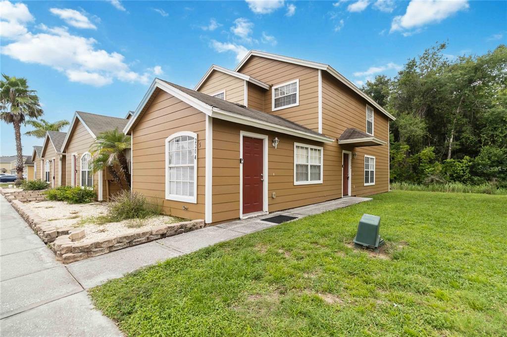 A two-story tan house with brown trim, a red front door, and a grassy yard — 2204 FAN PALM DRIVE, DAVENPORT, FL
