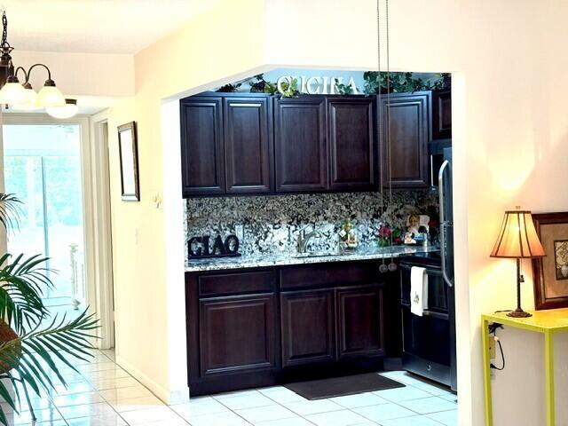 A kitchen features dark wood cabinets, granite countertops, and tiled floors — 12 Windsor A # 12, West Palm Beach FL 33417, WEST PALM BEACH, FL