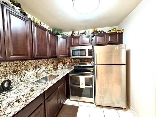 A kitchen features dark wood cabinets, granite countertops, and stainless steel appliances — 12 Windsor A # 12, West Palm Beach FL 33417, WEST PALM BEACH, FL