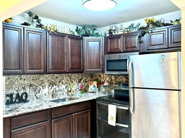 A kitchen features dark wood cabinets, granite countertops, and stainless steel appliances — 12 Windsor A # 12, West Palm Beach FL 33417, WEST PALM BEACH, FL