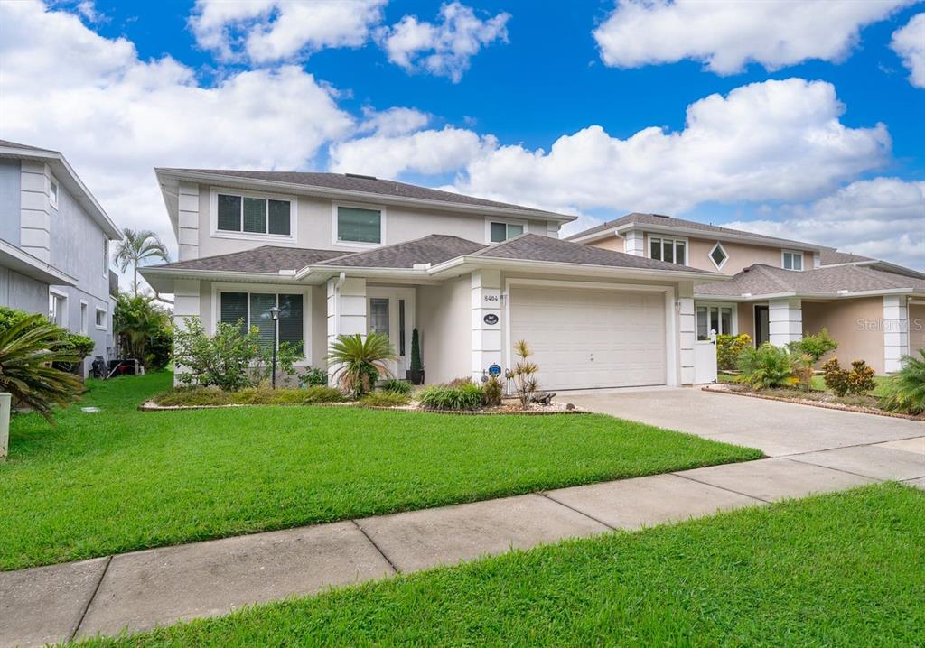 A two-story suburban house with a beige exterior, a two-car garage, and a front lawn — 8404 RISING STAR COURT, KISSIMMEE, FL