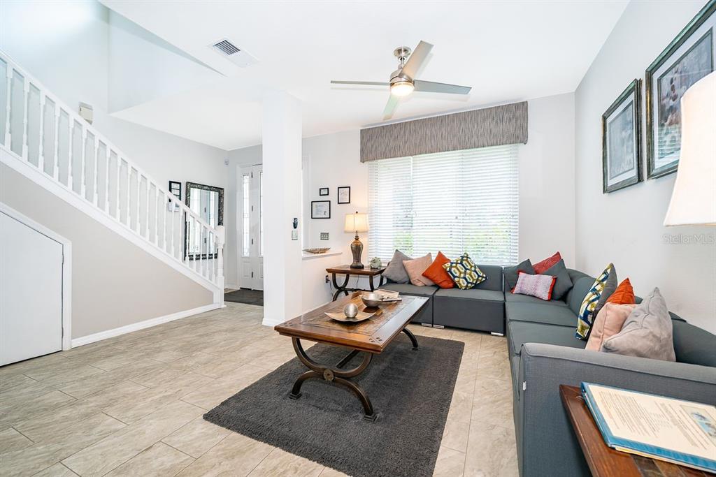 A living room features a sectional sofa, a coffee table, and a staircase with railings — 8404 RISING STAR COURT, KISSIMMEE, FL