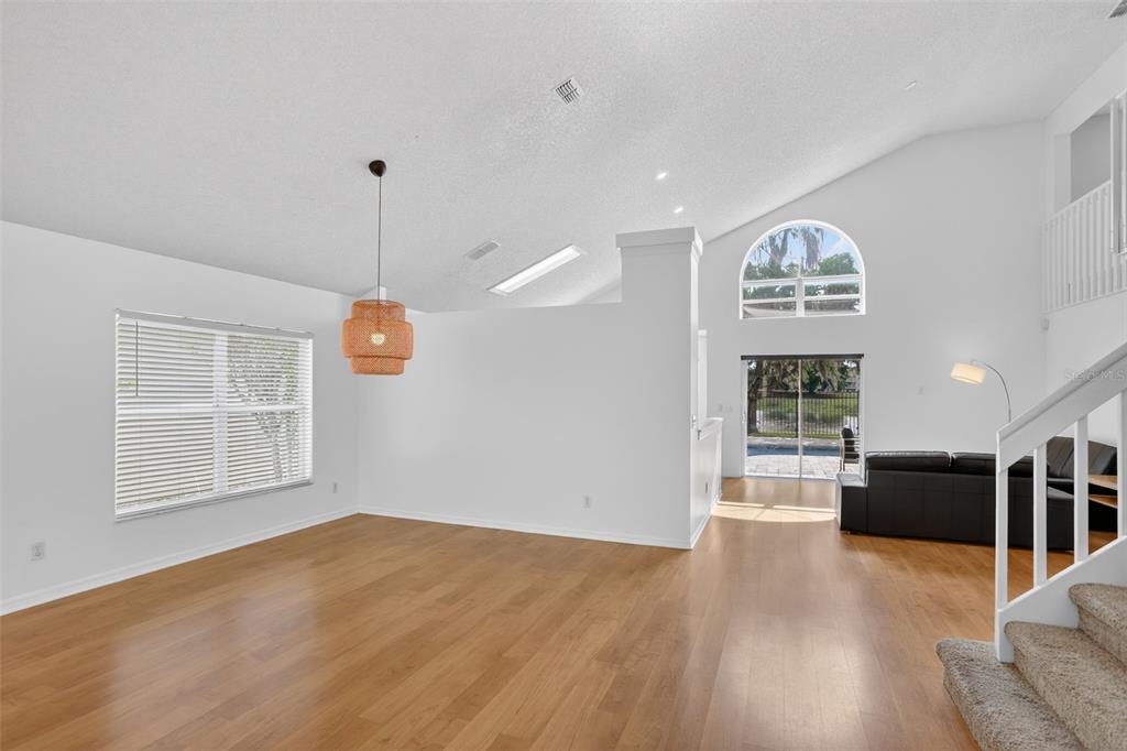 An open-concept living area with wood flooring, a vaulted ceiling, and a sliding glass door — 2809 RUNYON CIRCLE, ORLANDO, FL