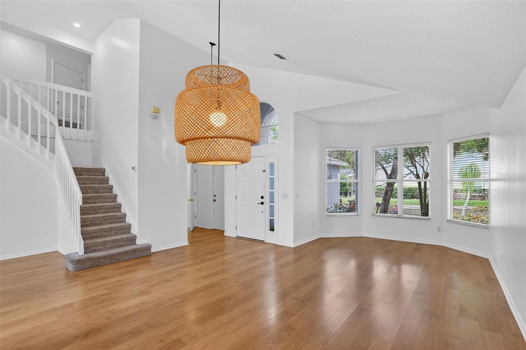 A bright living room features hardwood floors, a staircase, and a large woven pendant light — 2809 RUNYON CIRCLE, ORLANDO, FL