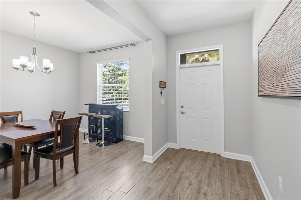 A dining room with wood-look tile flooring, a chandelier, and an adjacent entryway door — 472 BRUNSWICK DRIVE, DAVENPORT, FL