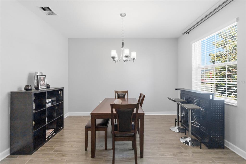 A dining room features a wood table, chairs, a black shelving unit, and a bar counter — 472 BRUNSWICK DRIVE, DAVENPORT, FL