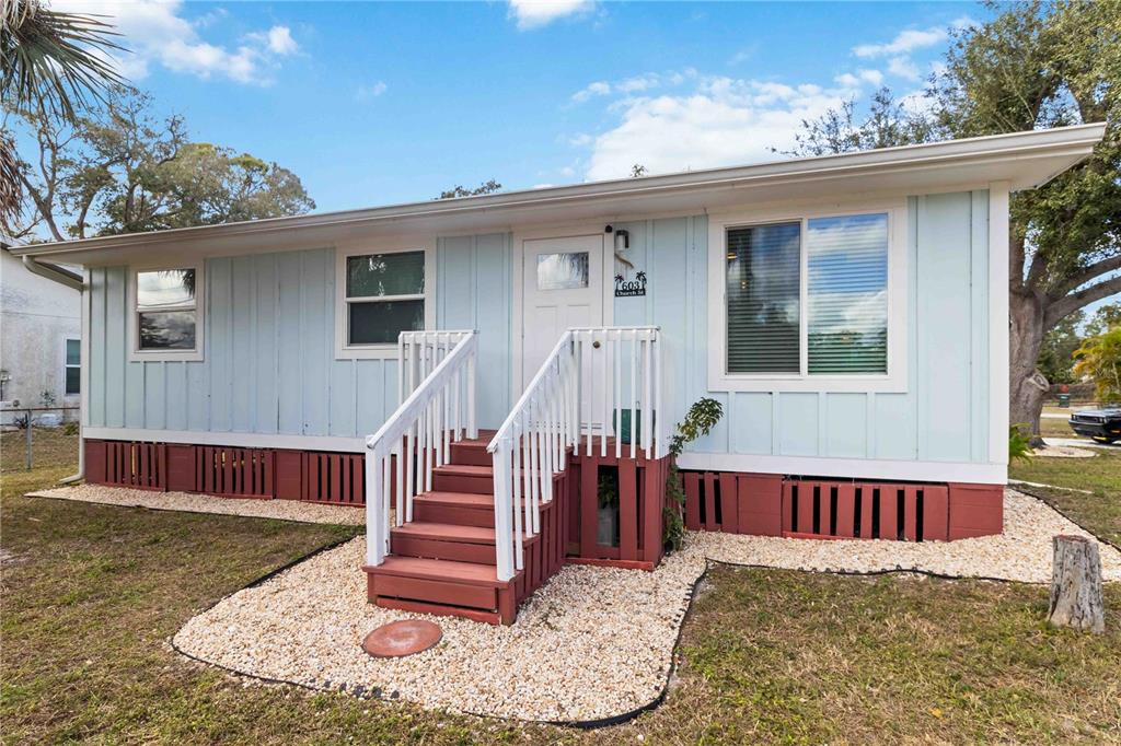 A light blue single-story house features a red foundation skirt and a wooden front staircase — 603 CHURCH STREET, NOKOMIS, FL