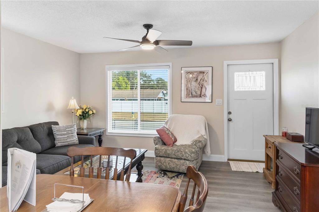 A living room features a gray sofa, patterned armchair, wood dining table, and ceiling fan — 603 CHURCH STREET, NOKOMIS, FL