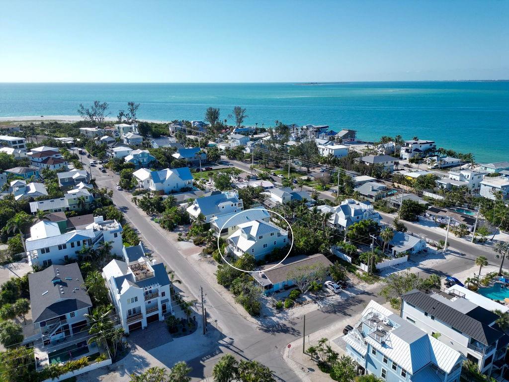An aerial view shows a coastal neighborhood with a circled house near the water — 704 GLADIOLUS STREET, ANNA MARIA, FL