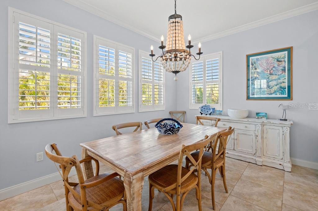 A kitchen with white cabinetry, granite countertops, a central island, and tile flooring — 704 GLADIOLUS STREET, ANNA MARIA, FL