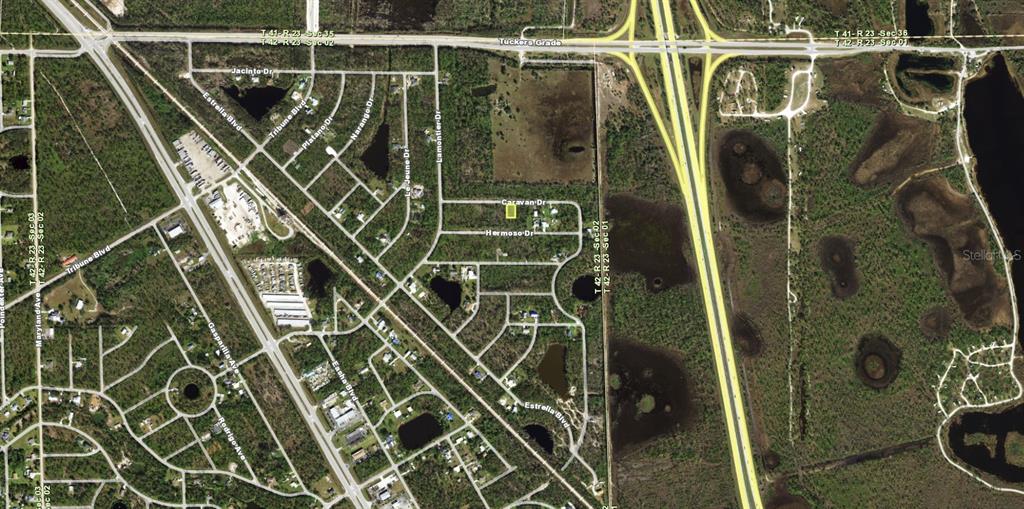 This aerial map shows a rectangular property lot highlighted in yellow within a residential neighborhood — 12193 CARAVAN DRIVE, PUNTA GORDA, FL
