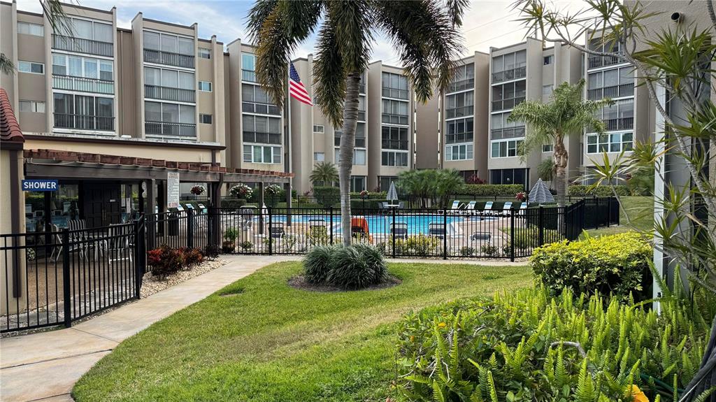 A swimming pool area is surrounded by a black fence and multi-story apartment buildings — 1243 S MARTIN LUTHER KING JR AVENUE UNIT B205, CLEARWATER, FL