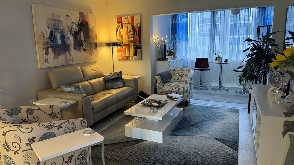 A living room features a beige sofa, patterned armchairs, a white coffee table, and area rug — 1243 S MARTIN LUTHER KING JR AVENUE UNIT B205, CLEARWATER, FL