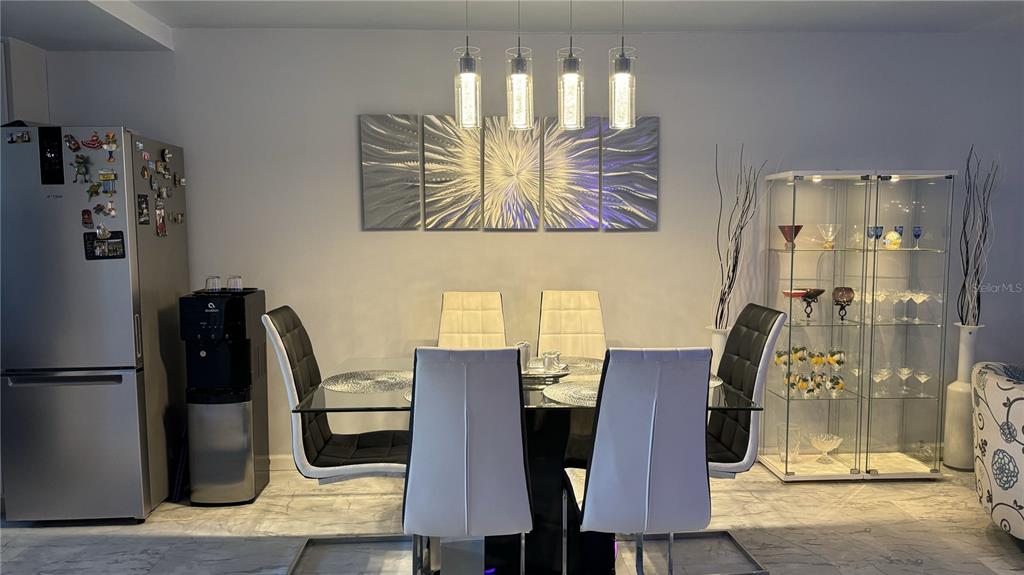 A dining room features a glass-topped table, six chairs, modern pendant lights, and wall art — 1243 S MARTIN LUTHER KING JR AVENUE UNIT B205, CLEARWATER, FL