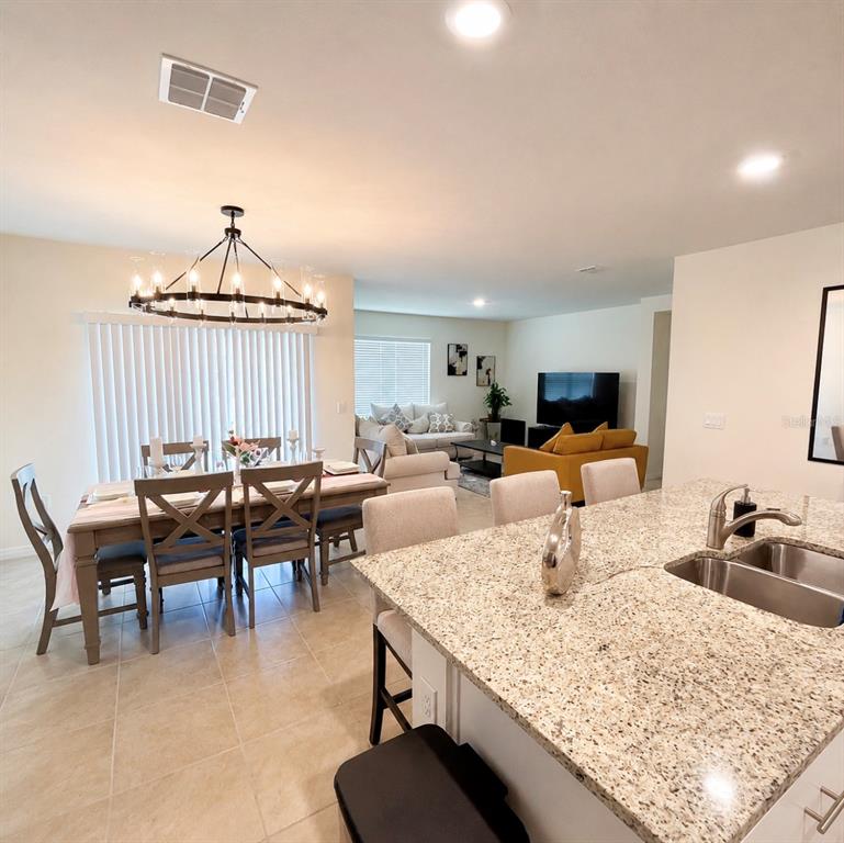 An open-concept kitchen with granite countertops overlooks a dining area and a living room — 1782 HIDEOUT STREET, KISSIMMEE, FL