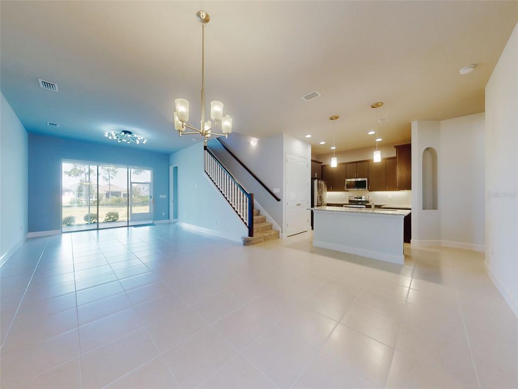 An open-concept living and dining area features tile flooring, a staircase, and a kitchen island — 6321 HANFIELD DRIVE, PORT ORANGE, FL