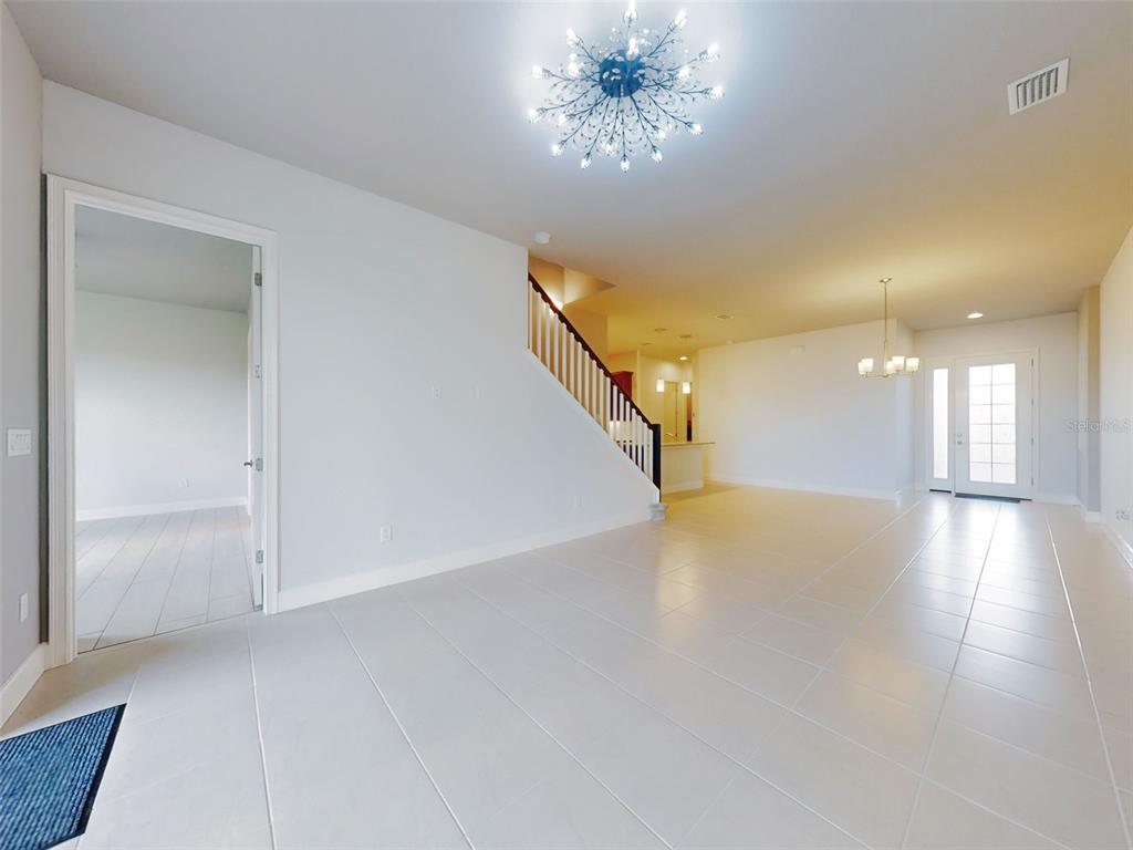 A bright, open-concept living area features light tile flooring, a staircase, and modern light fixtures — 6321 HANFIELD DRIVE, PORT ORANGE, FL