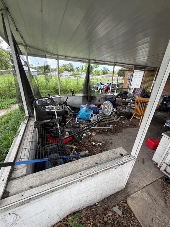 A cluttered, screened-in porch with a concrete floor and various items of stored equipment — 2880 SATURN DRIVE, TITUSVILLE, FL