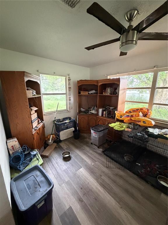 A room with wood-look flooring, a ceiling fan, two wooden cabinets, and pet crates — 2880 SATURN DRIVE, TITUSVILLE, FL