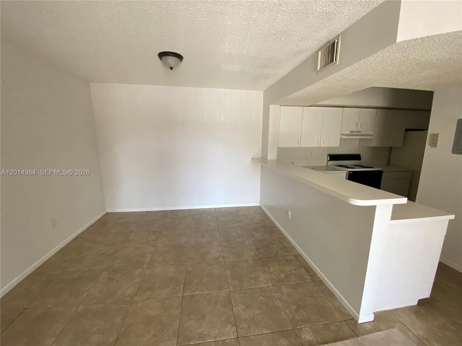An open-concept dining area features beige tile flooring and a breakfast bar facing the kitchen — 18820 NW 57th Ave # 203, Hialeah FL 33015, HIALEAH, FL