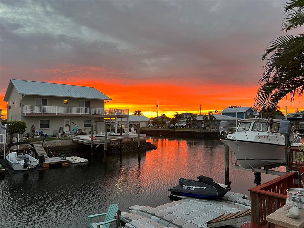 A canal-side house with a boat lift and jet ski at sunset — 13840 BARNARD AVENUE, HUDSON, FL