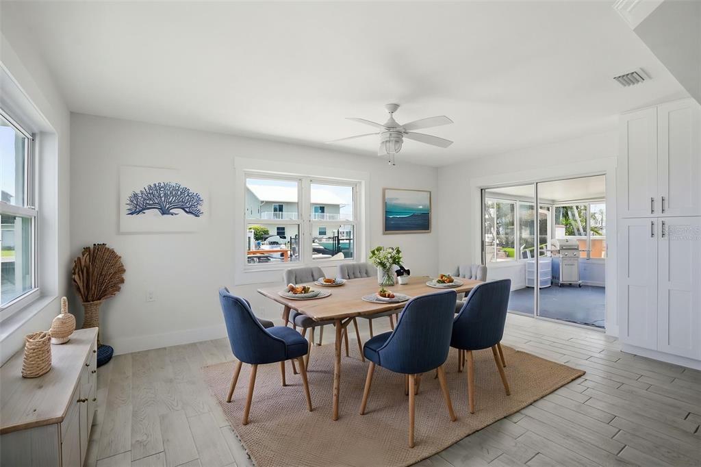 A dining room with a wooden table, blue chairs, a ceiling fan, and a sliding door — 13840 BARNARD AVENUE, HUDSON, FL