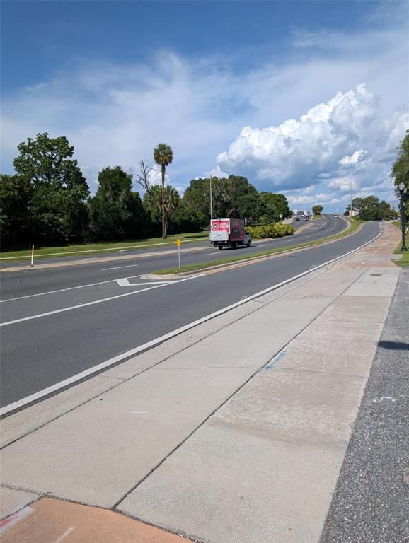 A paved road with a median and sidewalk stretches toward a distant horizon under clouds — 822 SW BROADWAY ST, OCALA, FL
