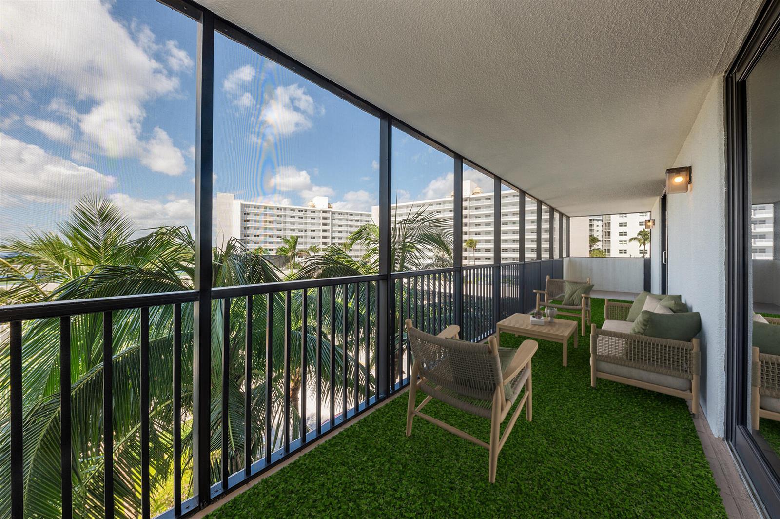 A screened-in balcony with artificial turf flooring, outdoor furniture, and views of nearby apartment buildings — 3400 S Ocean Boulevard # 4h, Highland Beach FL 33487, HIGHLAND BEACH, FL