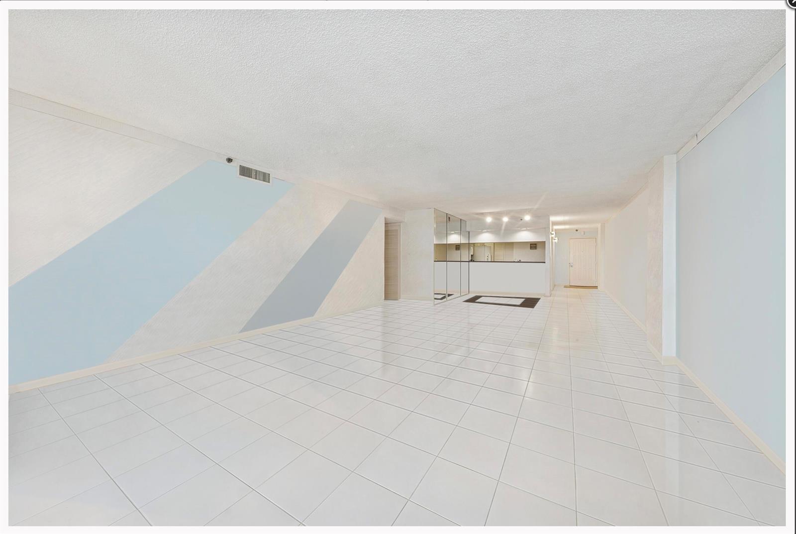 An empty room with white tile flooring, a textured ceiling, and blue diagonal wall accents — 3400 S Ocean Boulevard # 4h, Highland Beach FL 33487, HIGHLAND BEACH, FL