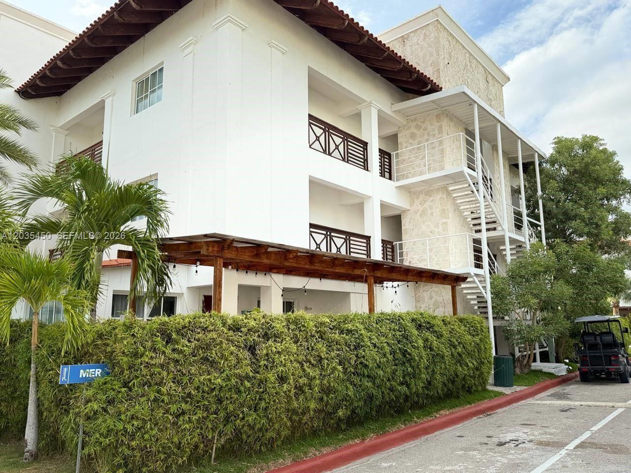 A three-story white building features balconies, an external metal staircase, and a wooden pergola — 1 La Altagracia # 1, FL