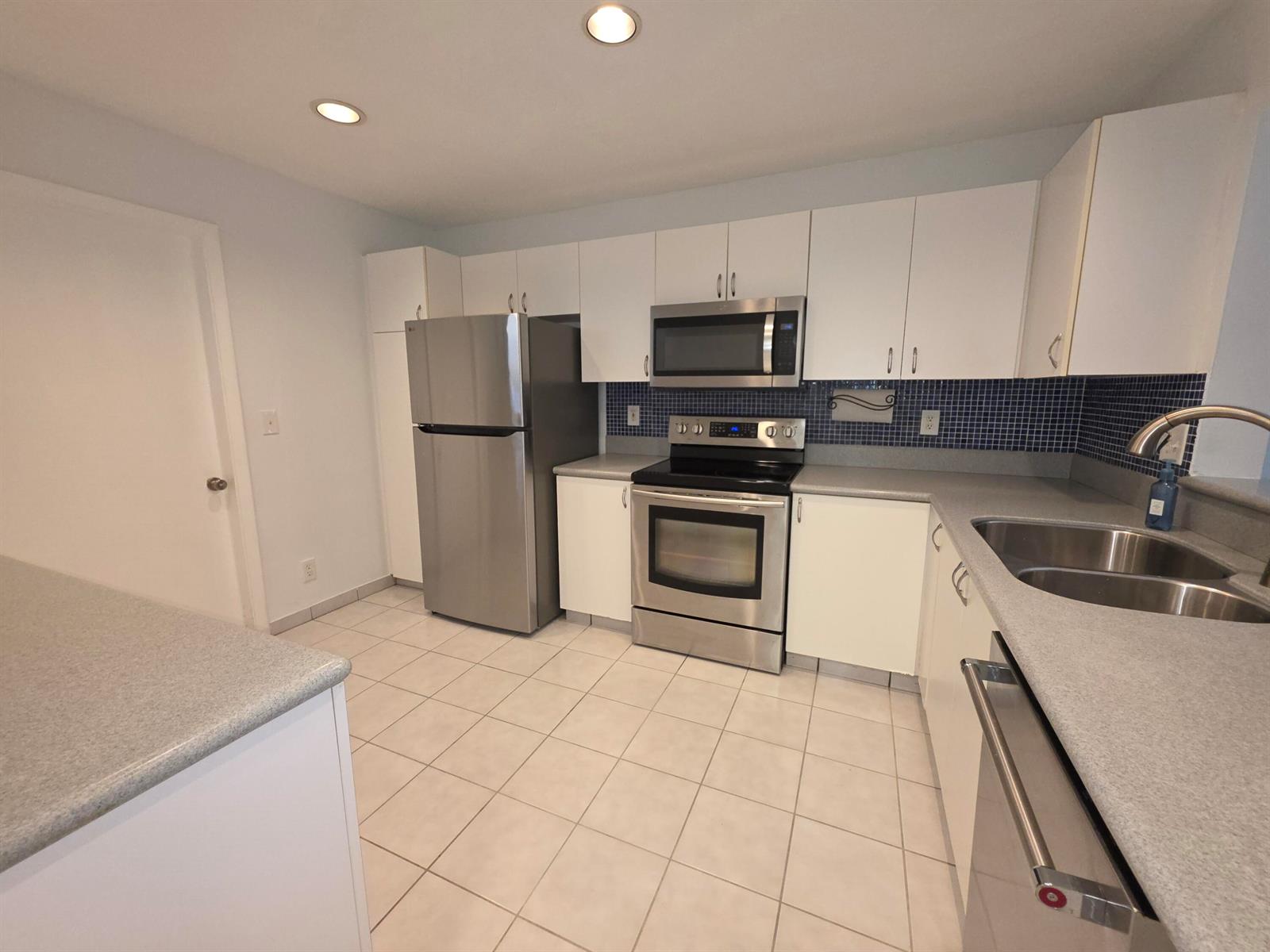 A kitchen features white cabinets, stainless steel appliances, gray countertops, and a blue tiled backsplash — 3767 NW 91st Lane, Sunrise FL 33351, SUNRISE, FL