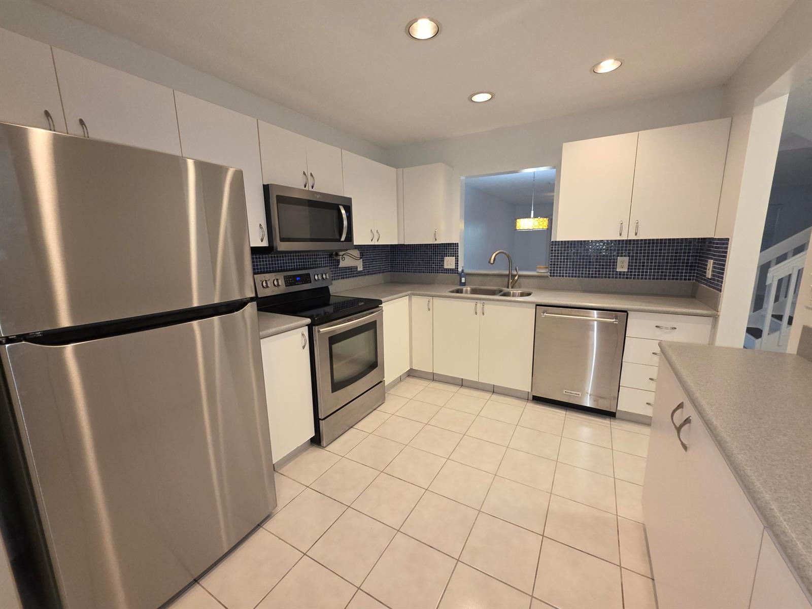 A kitchen with white cabinets, stainless steel appliances, blue tile backsplash, and light-colored floor tiles — 3767 NW 91st Lane, Sunrise FL 33351, SUNRISE, FL