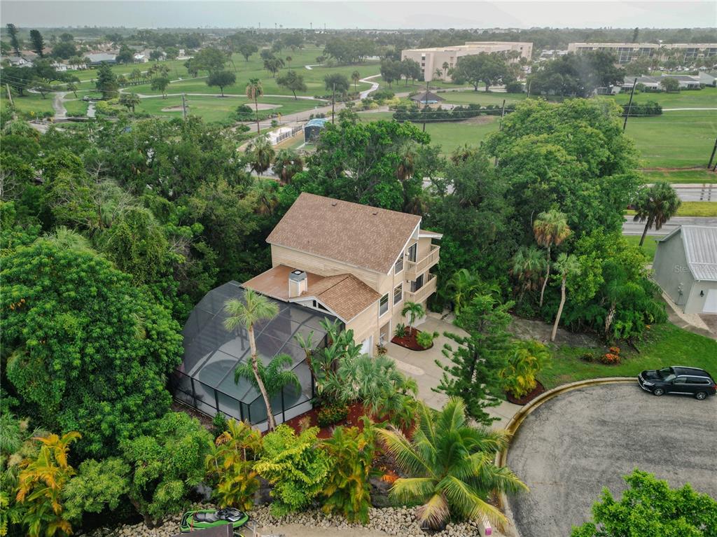 An aerial view shows a multi-story house with a screened pool and a golf course — 4003 BAYSIDE COURT, BRADENTON, FL
